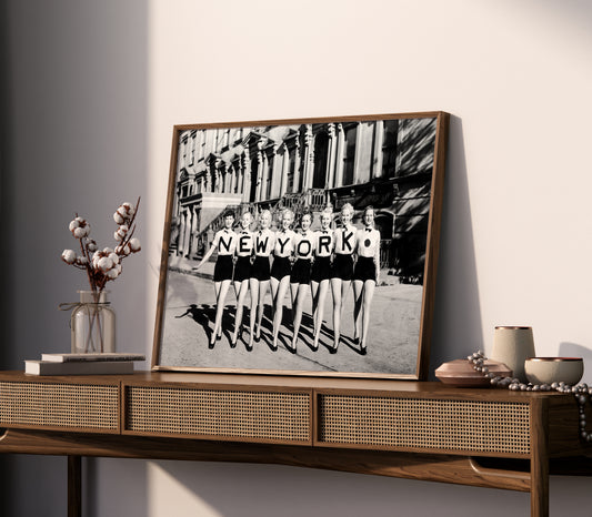 Vintage New York poster displayed in a bedroom, with eight women spelling NEW YORK across their shirts.