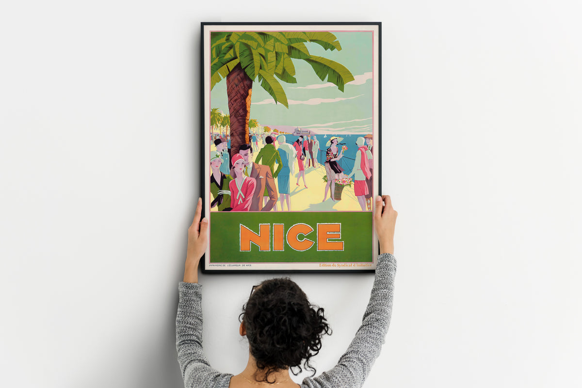 Nice coastal poster with a palm tree, seaside figures and orange text, shown being positioned on a wall