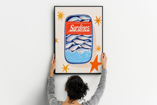 Large sardines poster with fish tin, blue waves and orange stars being positioned on a wall
