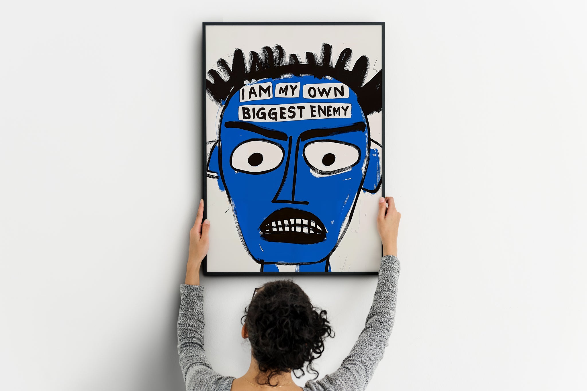 large Basquiat-style blue face poster being placed on wall, abstract portrait print
