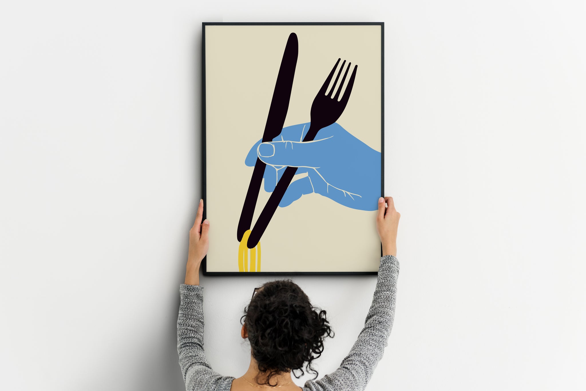 Person positioning a vertical noodles poster featuring a blue hand, fork, knife and yellow strands.