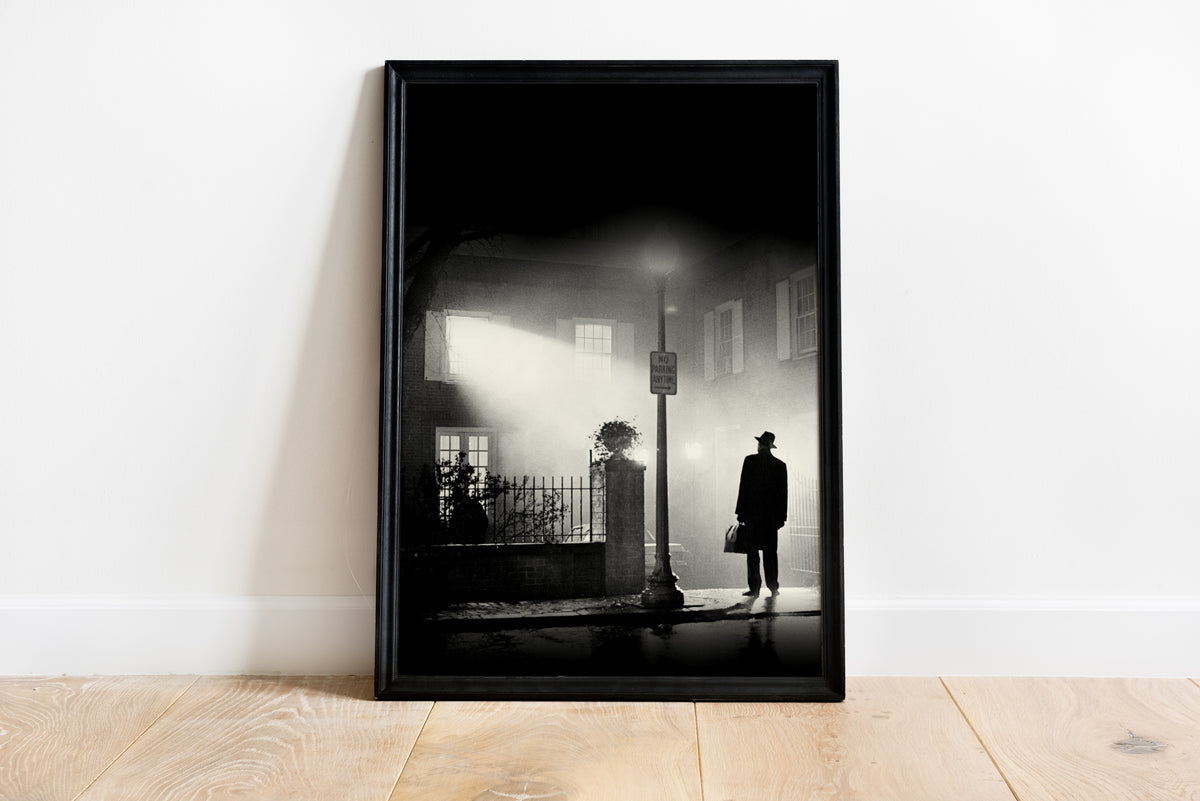 black and white Exorcist movie poster showing a solitary figure in a hat and coat standing on a wet street at night