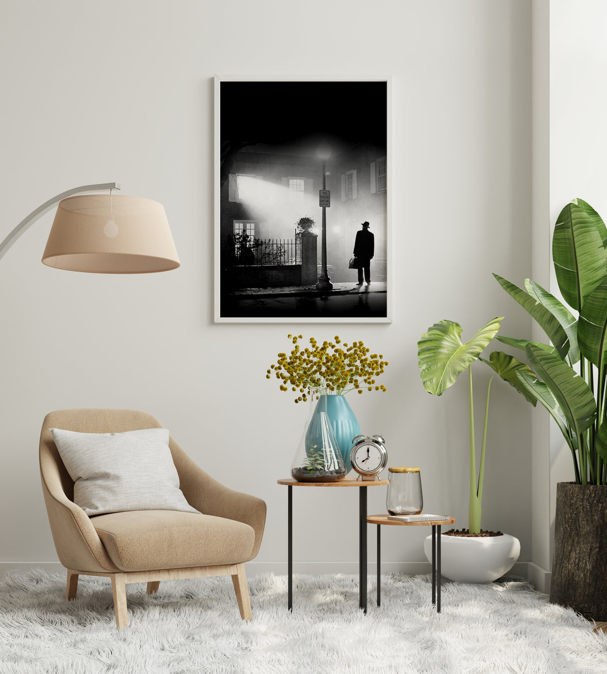 Exorcist movie poster showing a solitary figure in a hat and coat standing on a wet street at night, framed on a wall above a beige armchair and small side tables with a blue vase of yellow flowers and a silver alarm clock, and a large green plant in a white pot on a white shag rug.