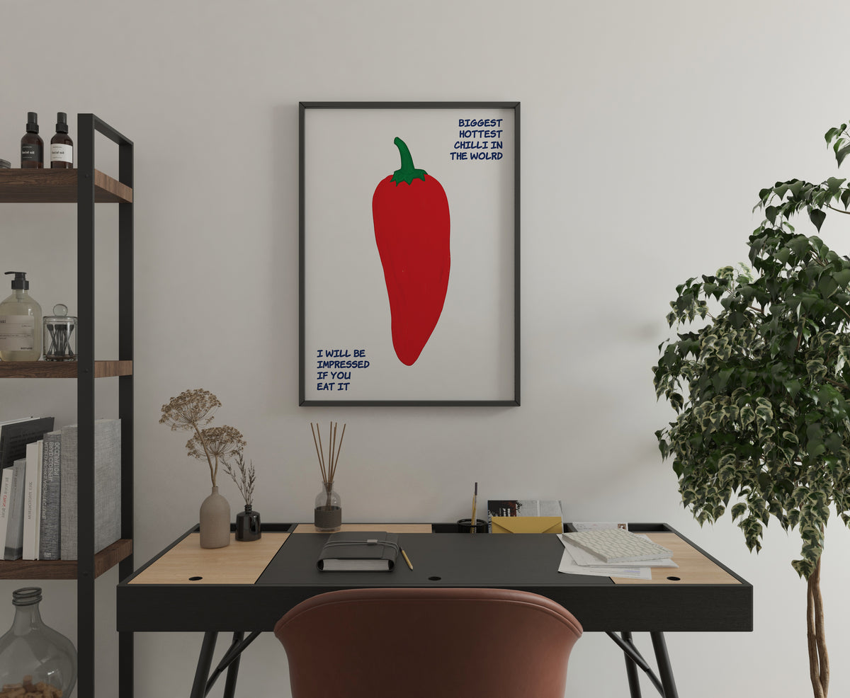 Humorous chilli pepper poster with oversized red pepper and blue lettering above a home office desk