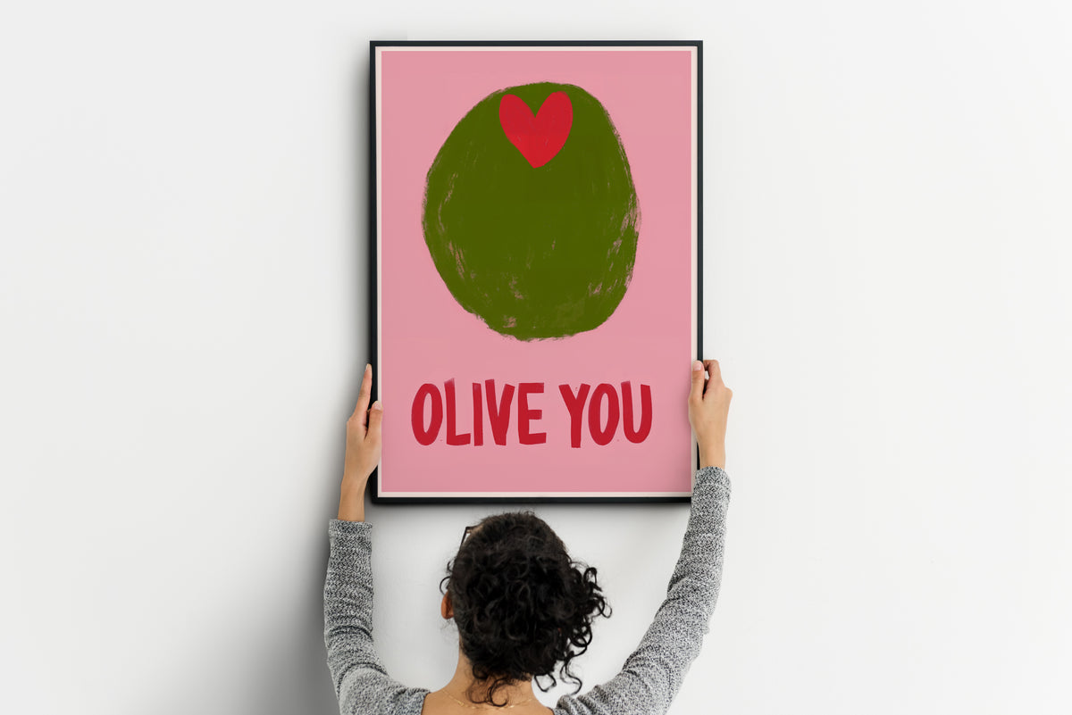 Large olive poster with red heart and OLIVE YOU text being positioned on a wall