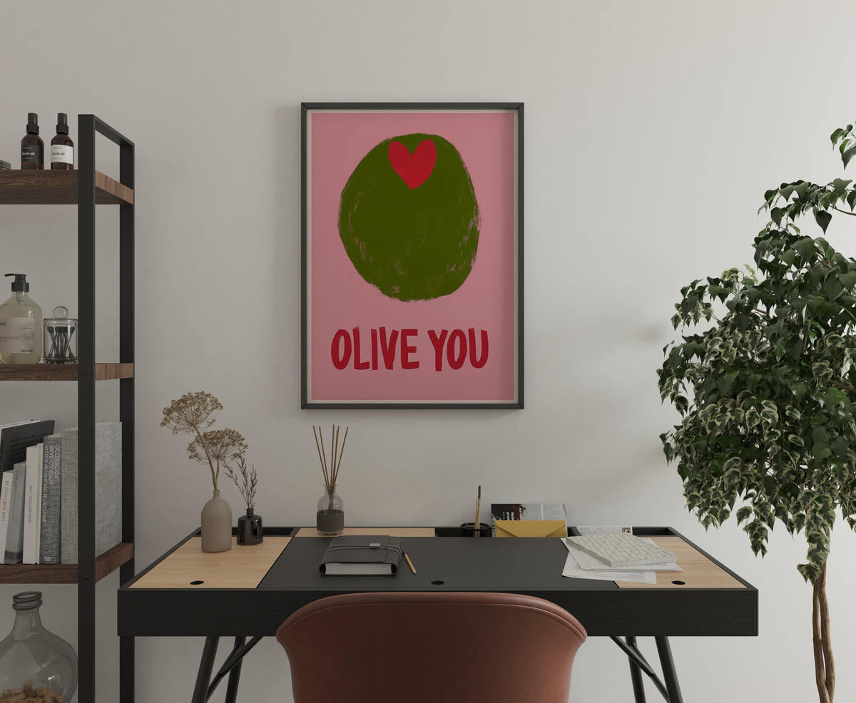 OLIVE YOU quote poster with green olive graphic displayed above a home office desk