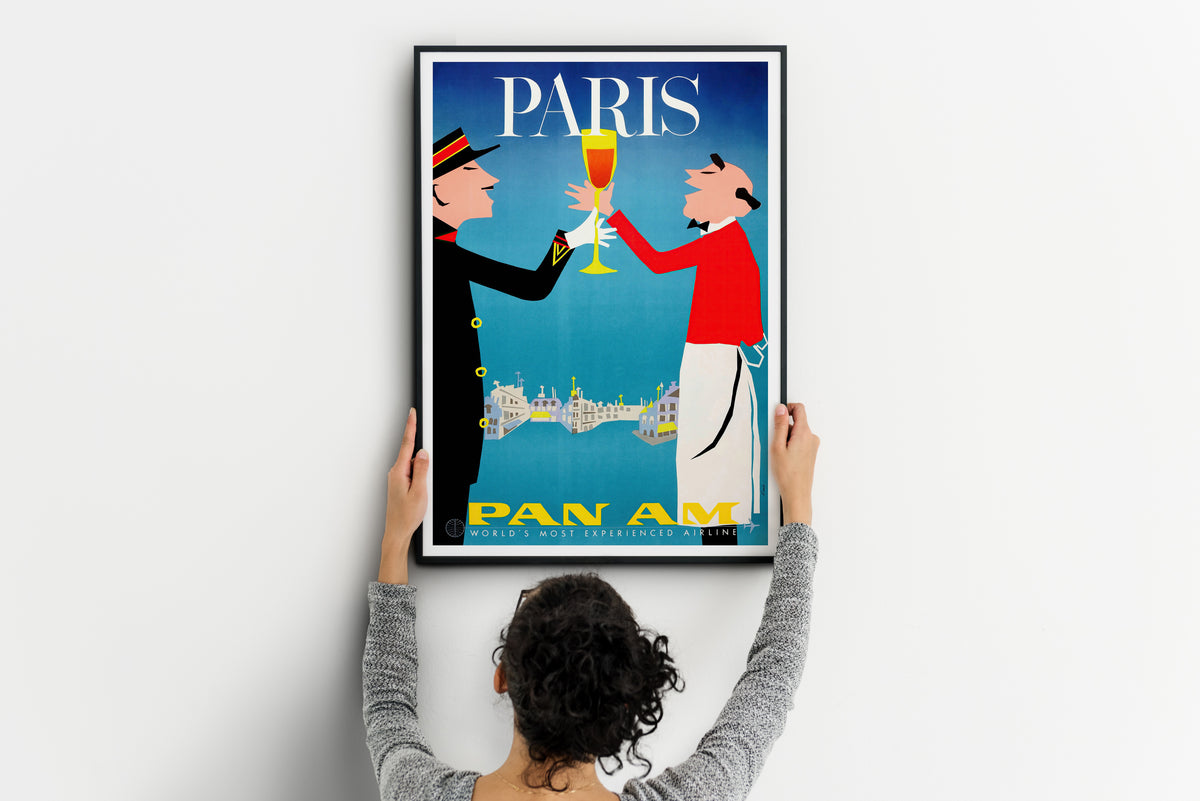 Paris Pan Am poster with two figures raising a glass shown during wall installation.
