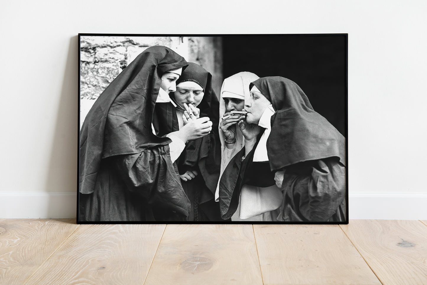 Smoking nuns poster showing four women gathered around cigarettes in a stark black-and-white photograph.