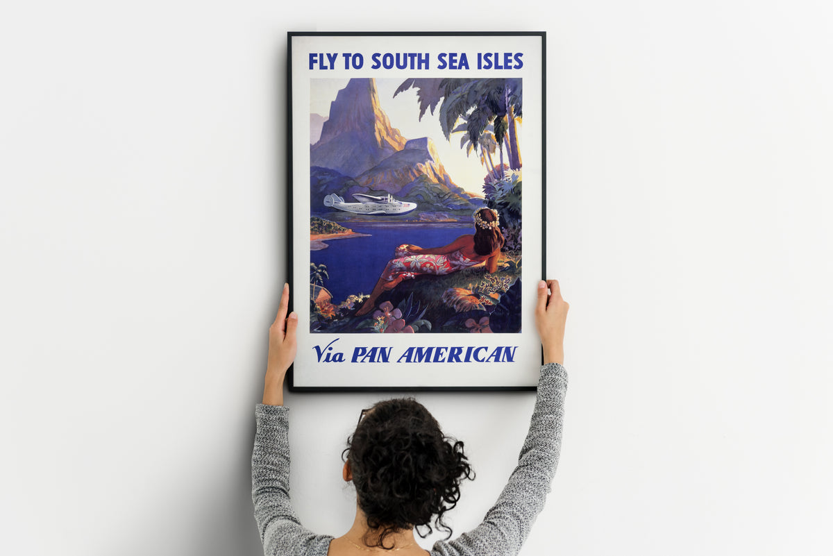 Pan American travel poster with mountain, lagoon, flying boat and tropical foliage.