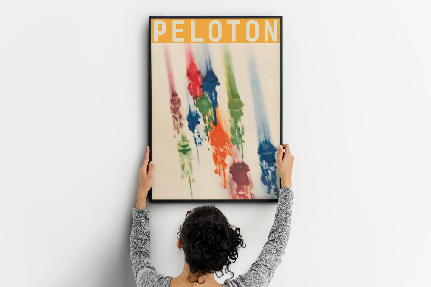large Peloton poster being placed on wall, colorful vintage cycling print