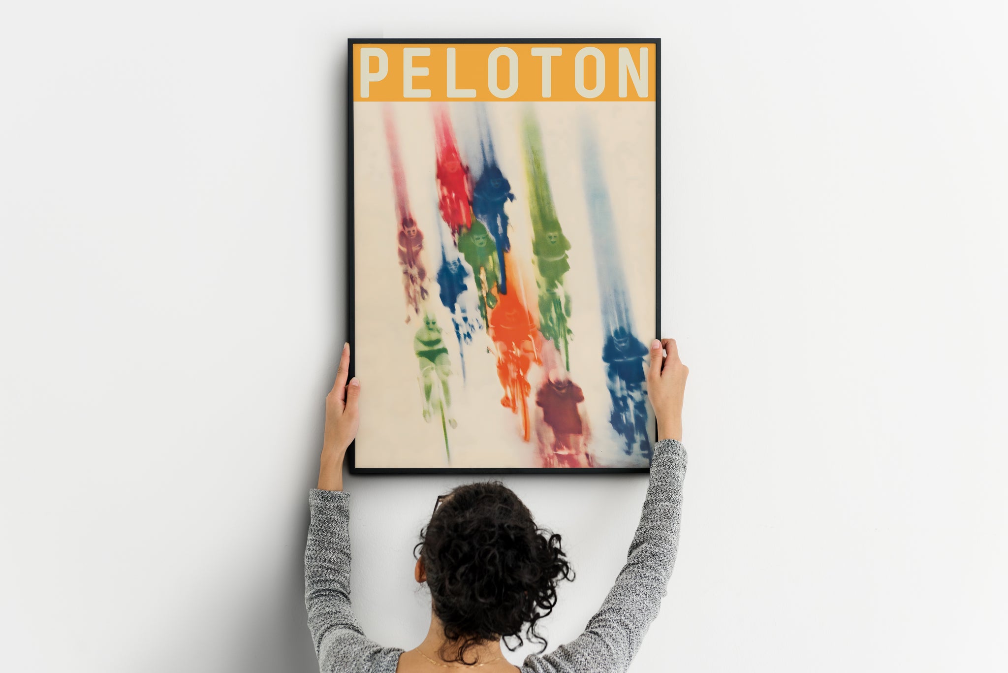 large Peloton poster being placed on wall, colorful vintage cycling print